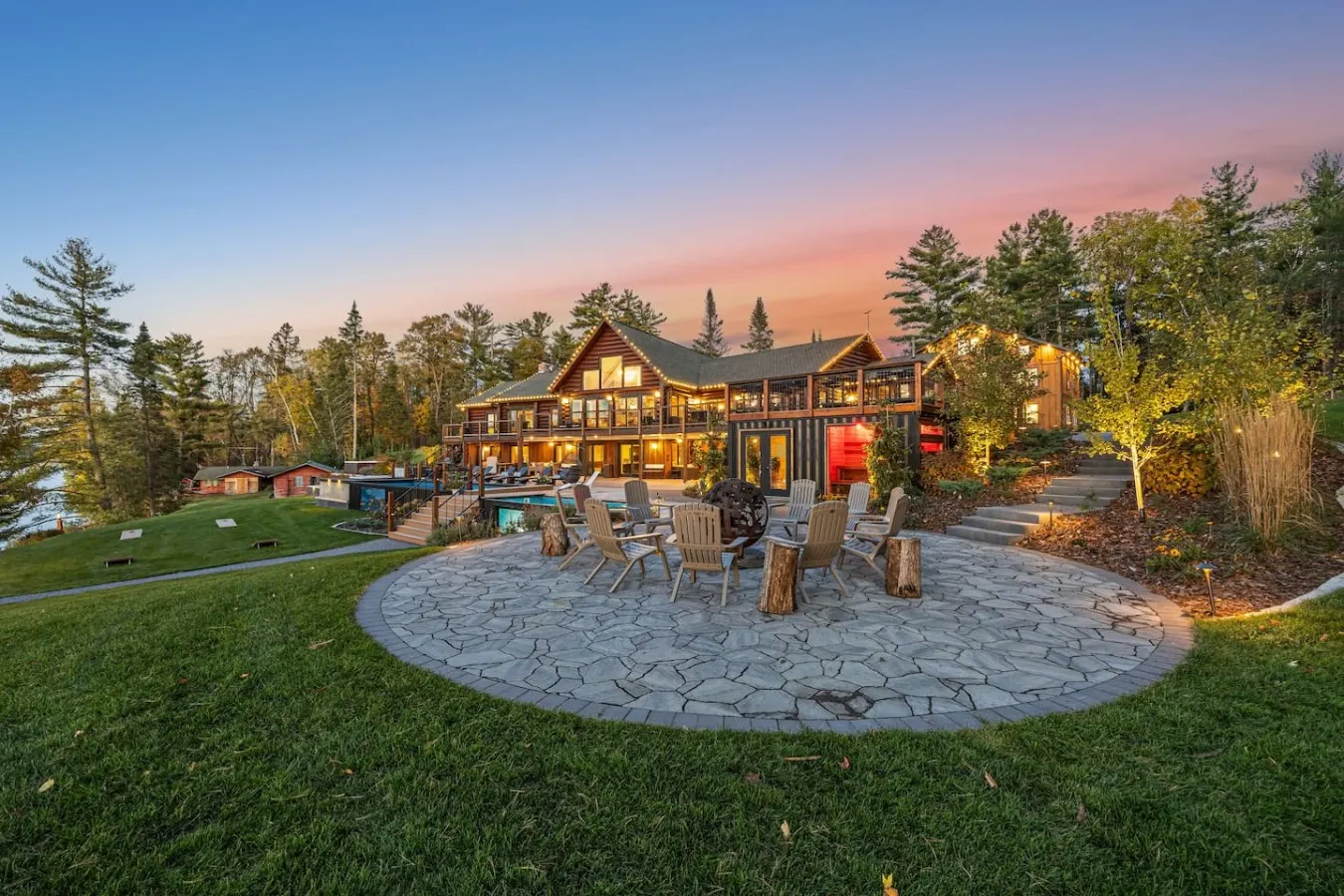 Stone fire ring with chairs in front of the lodge at sunset