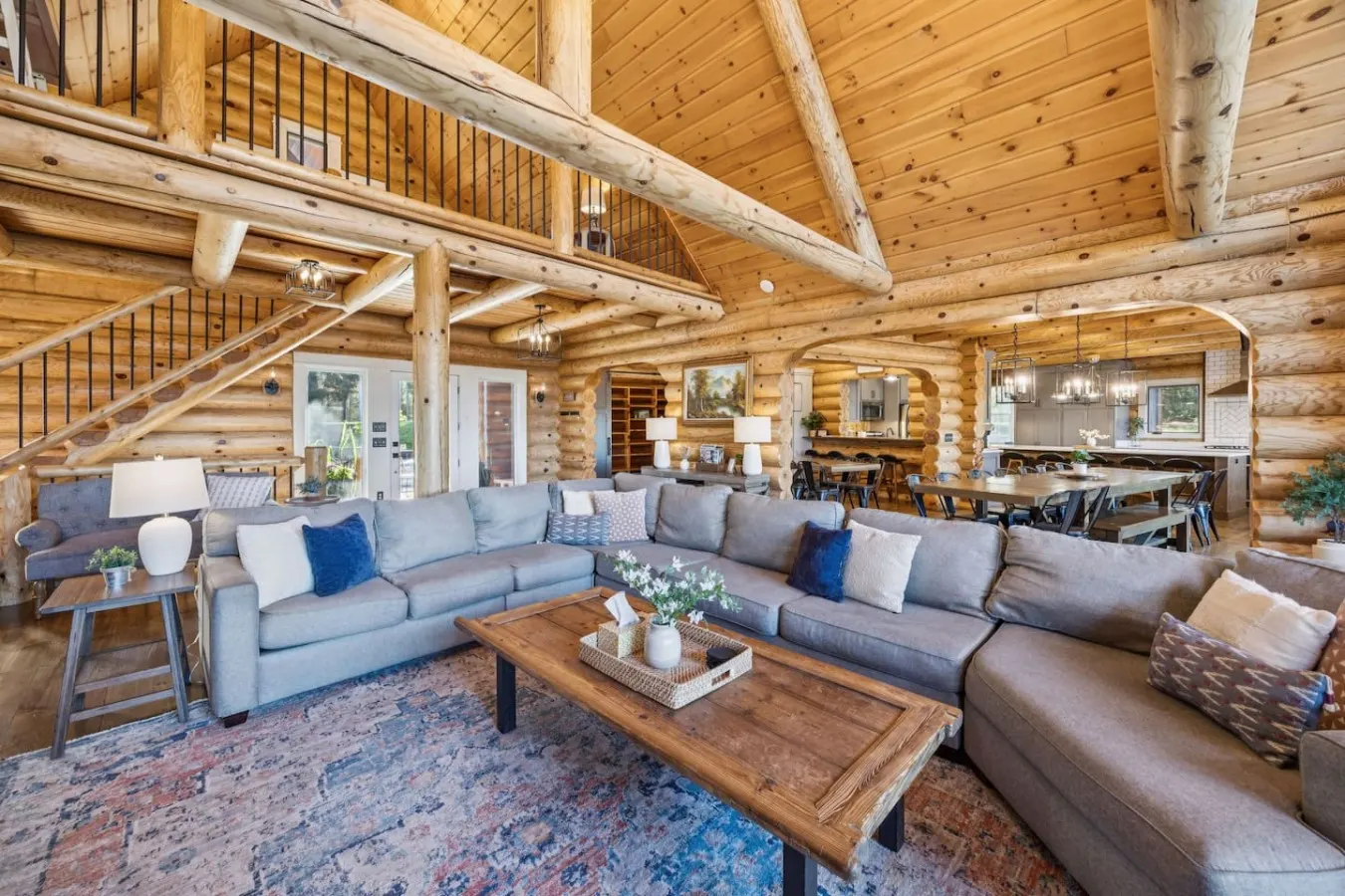 Vaulted log great room with sectional sofas and lake windows
